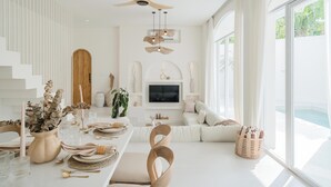 A modern dining area with a long table set for a meal, a ceiling fan, and a large window offering a view of the outdoors.