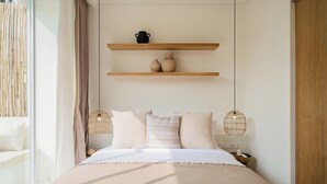 A bedroom with a bed, two bedside tables, a window with curtains, and a shelf with decorative items.