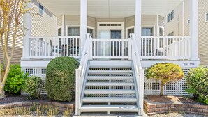 Une maison à deux étages avec un porche à l’avant, un escalier et une boîte aux lettres.