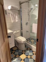 Une salle de bain avec des toilettes, une douche et un sol carrelé.