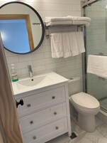 Un baño con un lavabo blanco, un inodoro, una cabina de ducha de vidrio y un espejo con marco de madera.