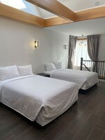 Een slaapkamer met twee bedden, een dakraam, een kroonluchter en een trap.