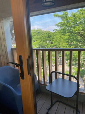Un balcone con ringhiera in legno, una sedia blu e un tavolo.