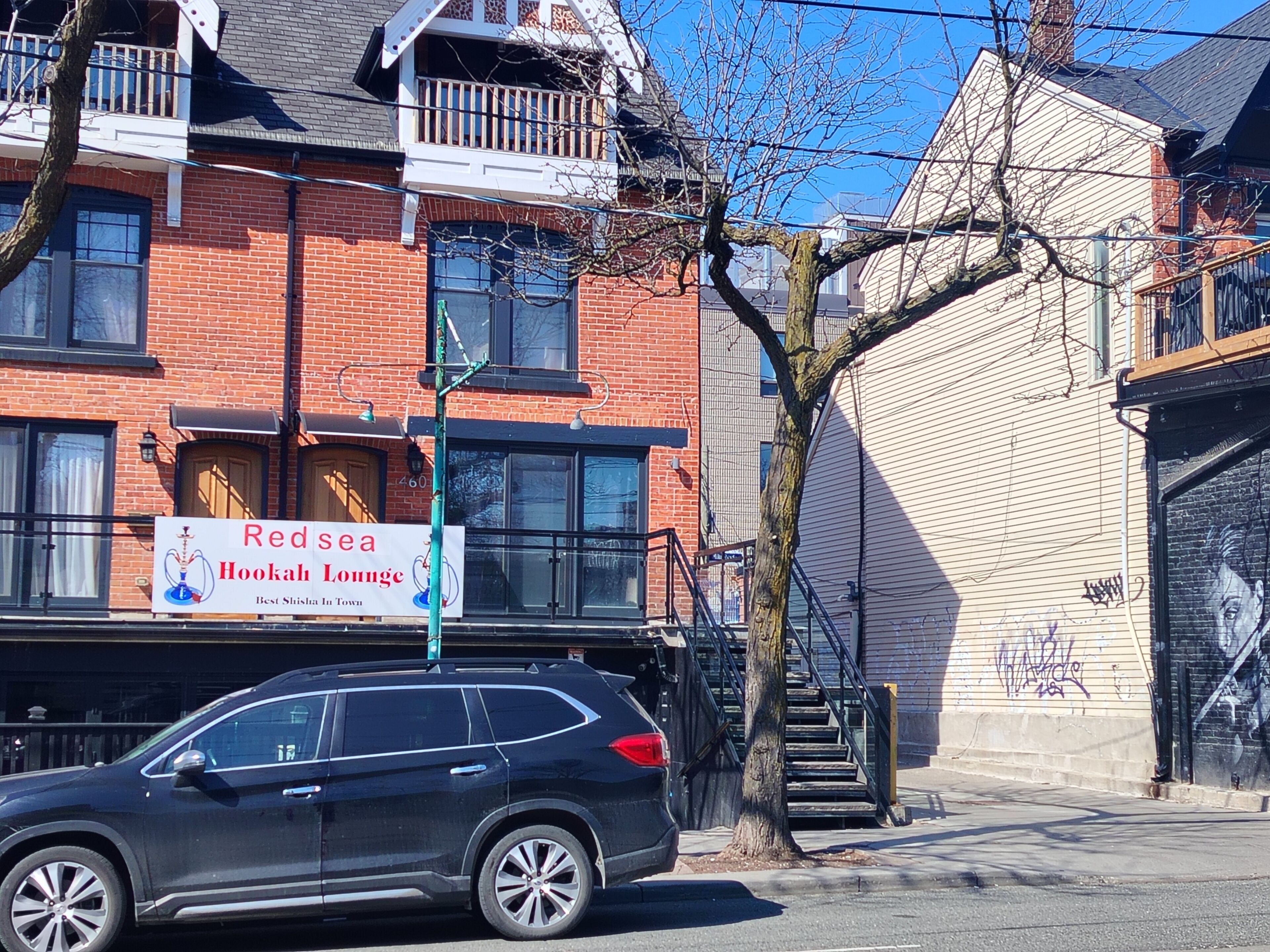 A Red Sea Hookah Lounge with a brick facade, a balcony, and a staircase leading to an upper level.