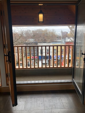 Una stanza con un balcone in legno, vista sulla strada e un lampadario.