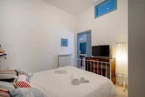 Un dormitorio con una cama, televisor, escritorio y una silla.