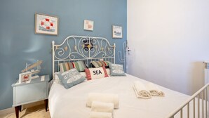 A bedroom with a bed, pillows, a nightstand, and wall art. - GuestHost - Charming apartment of about 35 sqm, perfect for 2 people, located on the second floor of a building without a lift.The property is located in the heart of the historic center of Monopoli, a few steps from the splendid Cathedral of Santa Maria (Monopoli)