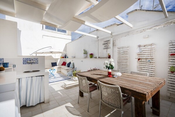 Una cocina y comedor integrados y luminosos, con una mesa de madera, armarios blancos y vistas al cielo.