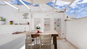 A rooftop terrace with a table and chairs, a potted plant, and a sign with directions. - GuestHost - Charming apartment of about 35 sqm, perfect for 2 people, located on the second floor of a building without a lift.The property is located in the heart of the historic center of Monopoli, a few steps from the splendid Cathedral of Santa Maria (Monopoli)