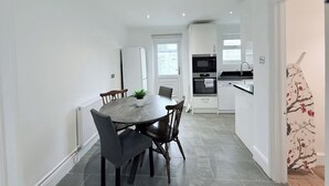 A modern kitchen with white cabinets, a built-in oven, and a microwave.