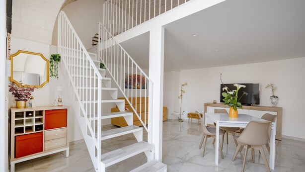A modern interior with a white staircase, a dining area, and a TV. - GuestHost - Dimora Marseglia (Ostuni)