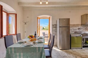 Un comedor con una mesa lista para dos, una cocina con electrodomésticos modernos y vistas a través de un vano abierto.