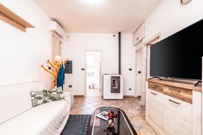 A compact living space with a sofa, a coffee table with books, a TV, a fireplace, and a wardrobe. - La Rosa dei Venti, Sorso, Italy (Sorso)