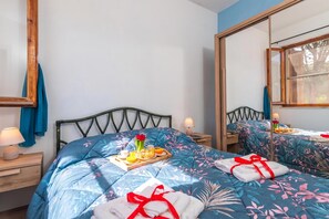 Ein Hotelzimmer mit Bett, Nachttisch, Spiegel und Fenster.