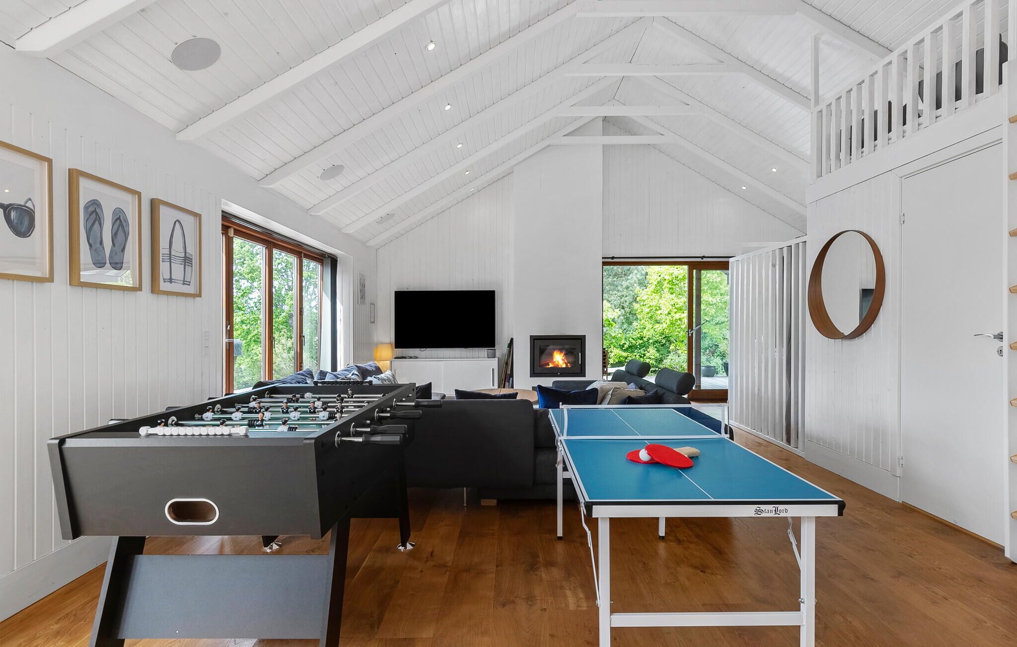 A spacious room with a foosball table, ping pong table, and a fireplace.