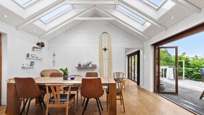 A dining area with a high ceiling and skylights, wooden furniture, and a surfboard decoration. - Cozy home in Vejby with sauna (Vejby)