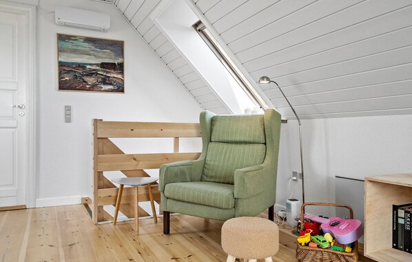 A cozy room with a wooden bench, a green armchair, a small round table, and a wicker basket with toys. - Gorgeous home in Vestervig with WiFi (Vestervig)