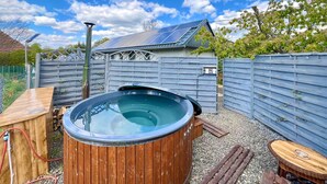 A hot tub in a backyard with a wooden deck, solar panels, and a fence. - Cozy home in Stankowice with sauna (Stankowice)