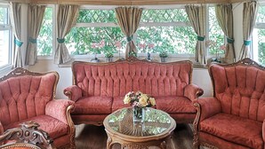 A room with a red upholstered sofa, two matching armchairs, and a small round table with a vase of flowers. - Cozy home in Stankowice with sauna (Stankowice)