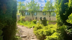 A garden pathway leading to a building with a tiled roof and windows. - Cozy home in Stankowice with sauna (Stankowice)