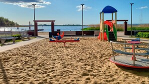 A beach with a playground, benches, and a view of the water.