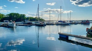 A marina with various boats docked, calm water, and a clear sky.