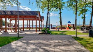 A park with picnic tables, a gazebo, playground equipment, and a view of the water.