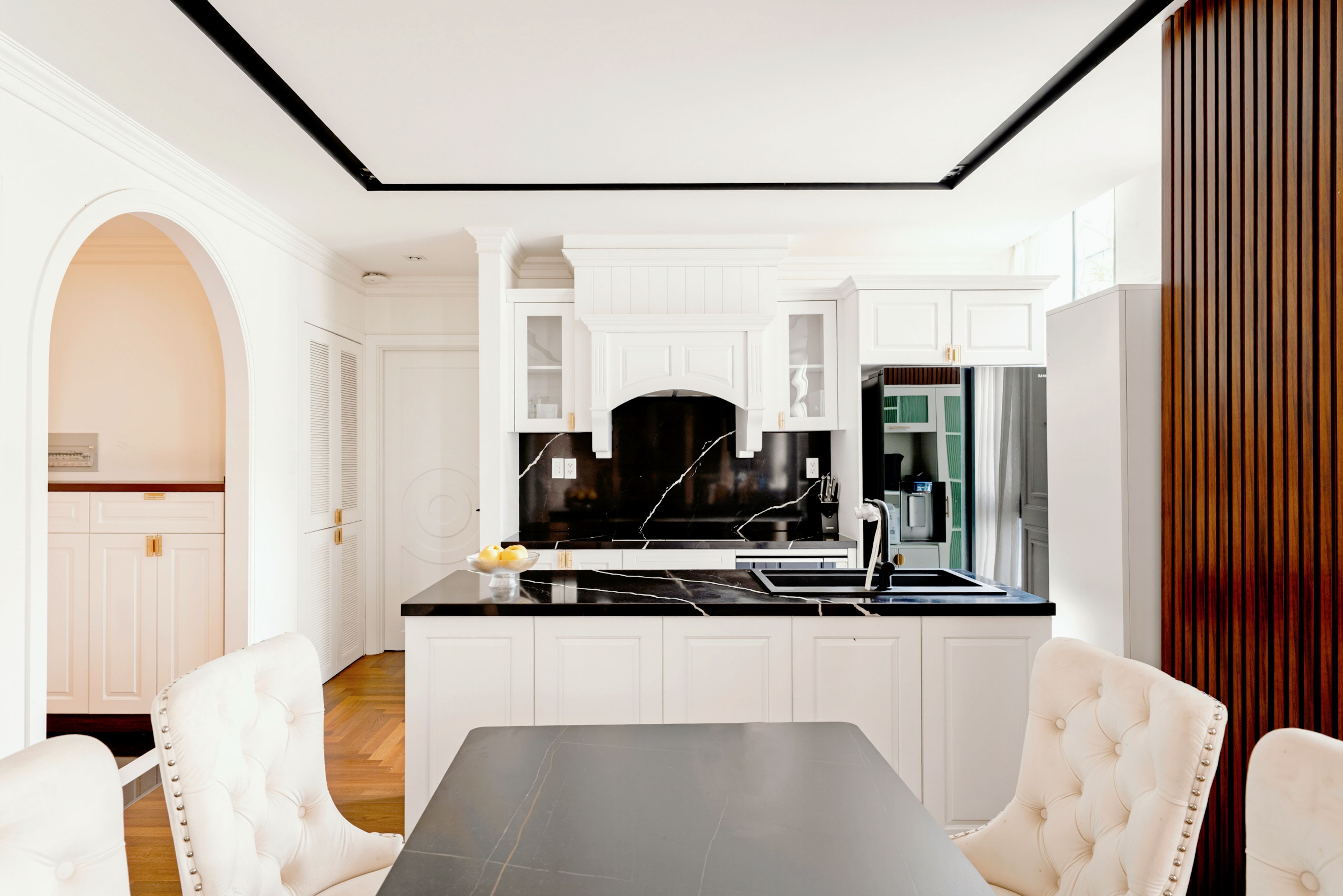 A modern kitchen with white cabinetry, a black countertop, and a central island with seating.