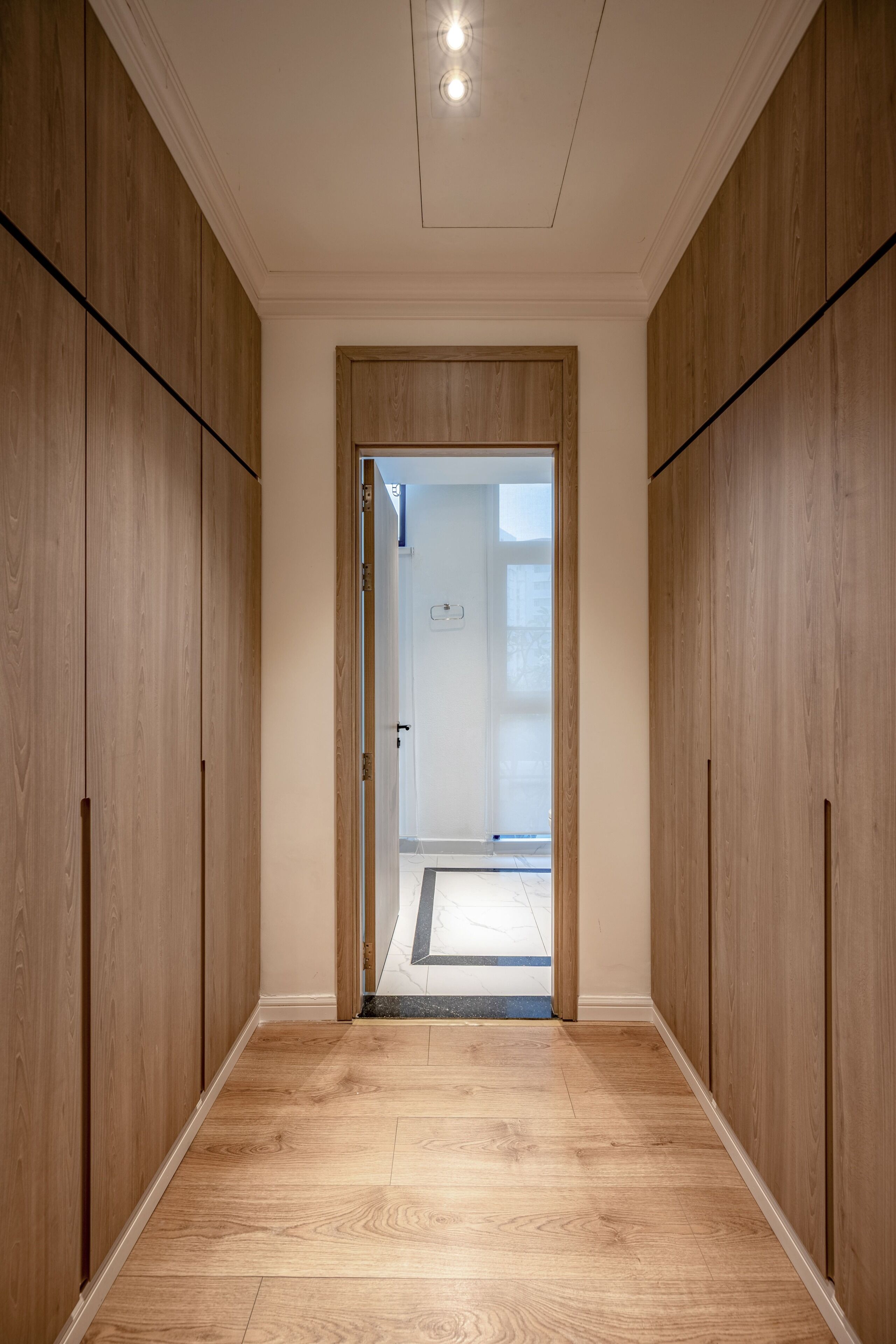 A hallway with wooden paneling, a door leading to another room, and a light fixture on the ceiling.