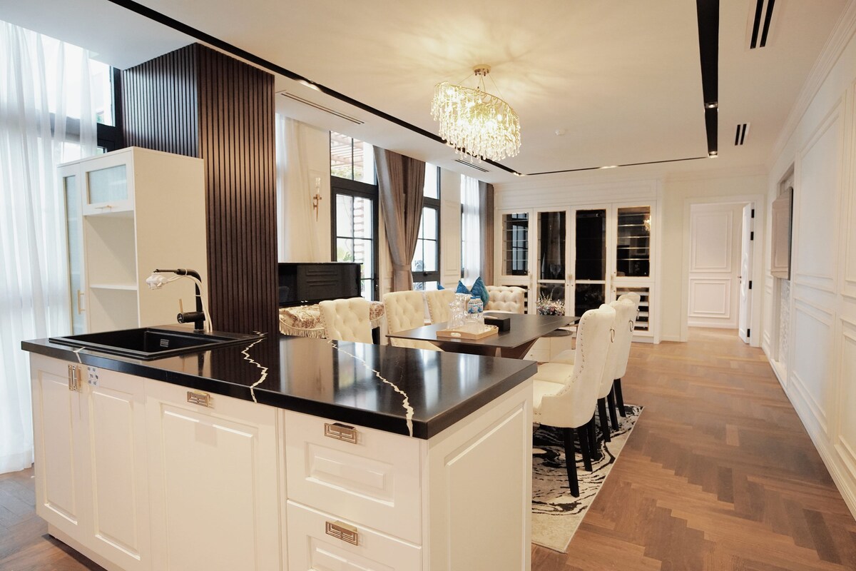 A modern kitchen with a central island, white cabinetry, and a chandelier.