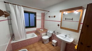 A compact bathroom with a bathtub, toilet, and sink.