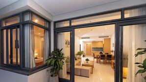 A modern interior with a large sliding glass door leading to a dining area and kitchen. There is a potted plant in the foreground. - BIG SALE | Full equipment apartment | Pool & beach (Đà Nẵng)