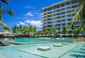 Ein Hotel mit großem Poolbereich, mehreren Balkonen und Palmen.