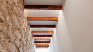 Una escalera con vigas de madera y un muro de piedra.