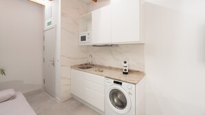 Una cocina compacta con lavadora integrada, microondas y lavamanos.