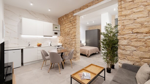 A modern kitchen with white cabinets and a stone accent wall.
