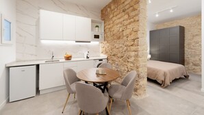 A modern kitchen with white cabinets, a marble backsplash, and a stone accent wall.