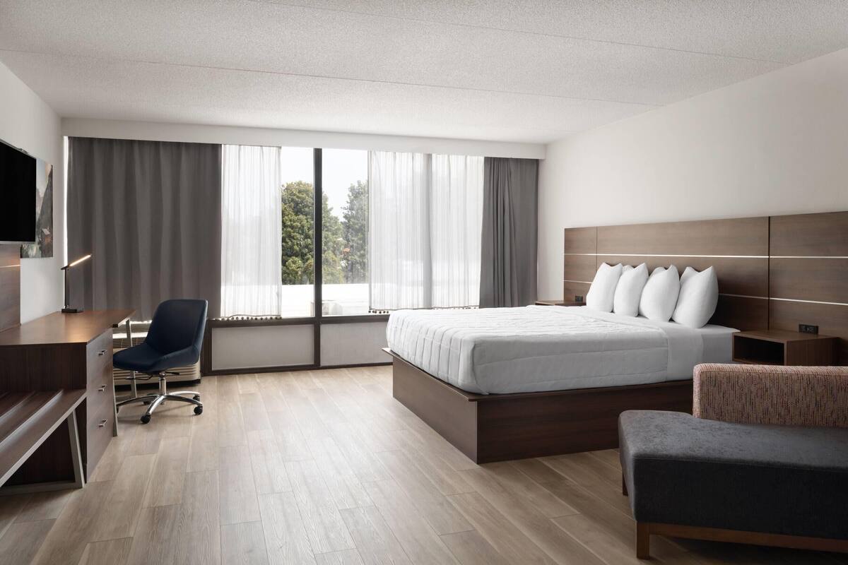 A modern hotel room with a large bed, a desk, and a chair.