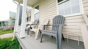 Een veranda met Adirondack-stoelen en een kleine tafel.