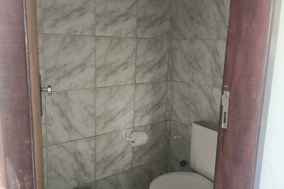 A small, enclosed bathroom with a toilet and a trash bin.