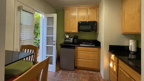 A compact kitchen with wooden cabinets, a microwave, a toaster, and a refrigerator. - BESO DEL SOL (Huntington Beach)