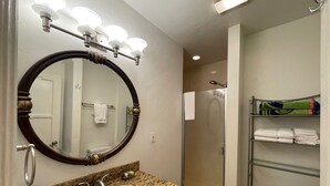 A bathroom with a large mirror, a sink, a shower, and a towel rack. - BESO DEL SOL (Huntington Beach)