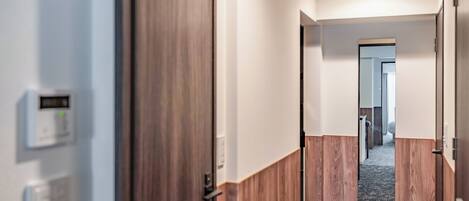 A hallway with wooden doors and a modern thermostat on the wall.
