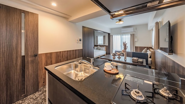 A modern kitchen with a built-in gas stove, stainless steel sink, and a wooden countertop. - Apartment Hotel 11 Abeno (Osaka)