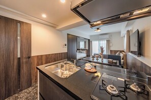 Eine moderne Küche mit eingebautem Gaskochfeld, Spüle aus Edelstahl und einer Holz Arbeitsplatte.