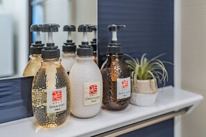 En hylde med forskellige toiletartikler, herunder shampoo, balsam og sæbe.