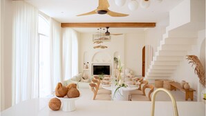 A modern living room with a dining area, a staircase, and a fireplace.