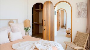 A bedroom with a bed, a chair, a wardrobe, and a mirror.
