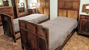 A bedroom with two wooden beds, a dresser, a mirror, and a nightstand with a lamp.