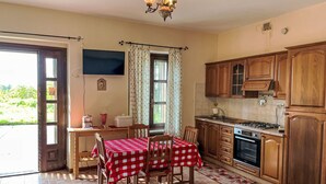 A kitchen with wooden cabinets, a dining table with a red and white checkered tablecloth, and a chandelier.